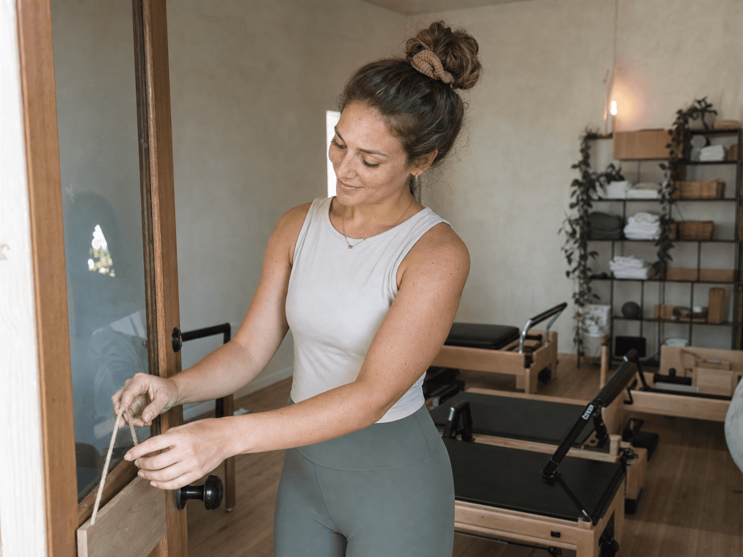 A first-time owner hanging a small sign on the door of her new Pilates studio